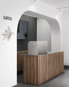 A modern lobby featuring a wooden reception desk with a metallic partition and a flat-screen TV mounted on the back wall.
