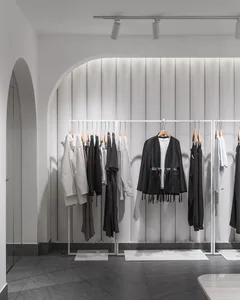 Modern minimalist clothing retail store with metal frames and clothing racks.