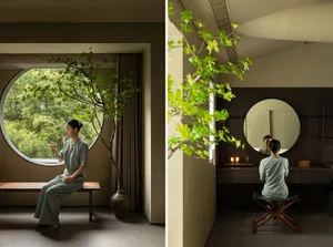 A modern minimalist living room with a round window, glass table, wooden floor, and indoor plants.