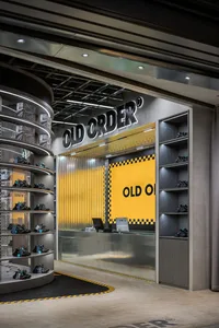 A modern retail store with a concrete and metal interior featuring a circular display and a yellow wall.
