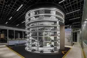 A modern retail shoe store interior with a metal spiral shelving unit displaying shoes.