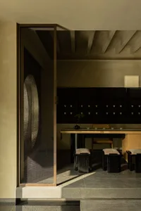 A minimalist tea room featuring wooden furniture, stone flooring, and glass elements.