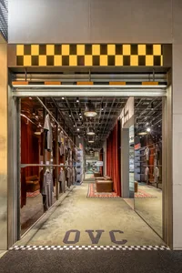 An industrial-style clothing store interior with concrete flooring and walls, featuring clothes displayed on racks.