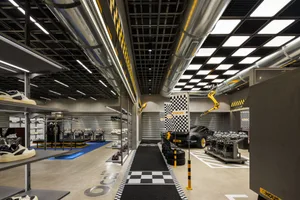 寬敞的汽車零售店，搭配金屬柱、格紋地板，以及黑黃配色。