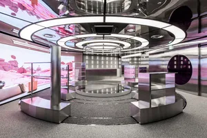 A futuristic, metallic interior design featuring a circular stage with a pink and purple color scheme.