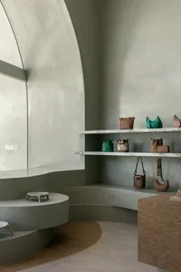 A contemporary retail store interior featuring modern concrete and marble shelving units showcasing minimalist bags.
