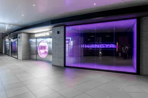 現代店面擁有紫色照明窗戶、金屬與玻璃元素、磚牆，以及夜間燈光。