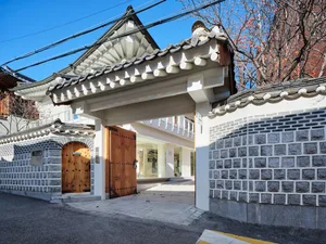 A traditional South Korean building facade featuring a stone wall and wooden arched doorway.