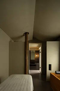 A minimalist bedroom with concrete walls and a bed.