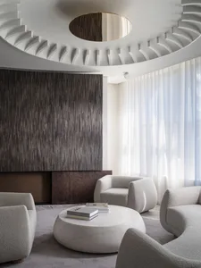 Modern living room with a marble coffee table and textured fabric furniture, featuring circular ceiling design.