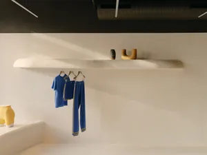 Modern, minimalist industrial showroom with concrete walls and minimalist shelves displaying minimalist clothing.
