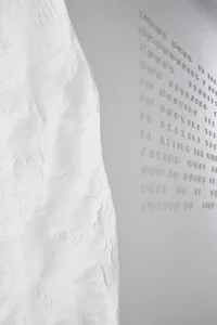 White plaster sculpture with text relief on a gray background