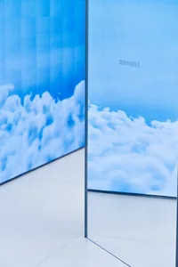 極簡室內設計，玻璃牆映照著多雲的天空背景。