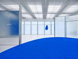 現代極簡室內，搭配藍色地毯、玻璃與金屬表面。