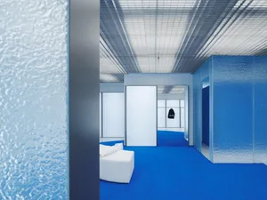 A minimalist office space featuring glass walls and high ceilings.
