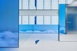 Modern minimalist office space with glass panels and cloud imagery on the walls and floor.