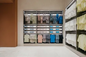 極簡風格的零售店展示區，架上整齊陳列服裝商品，置於現代且光線充足的環境中。