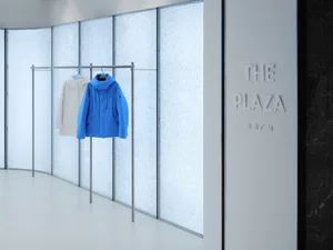 A clothing shop interior with modern design, glass walls, and metal railings.