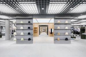 A minimalist clothing store with concrete shelves displaying various hats.
