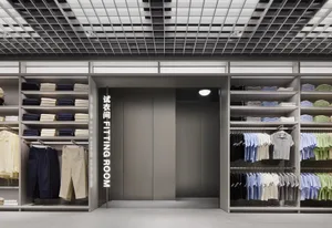 A minimalist clothing store with metallic finishes featuring a fitting room sign.