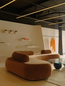 A modern living room featuring a comfortable velvet sofa, sleek coffee table, and minimalist decor.