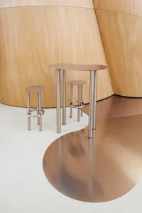 Three modern metal tables with unique curved shapes and stools in a contemporary setting.