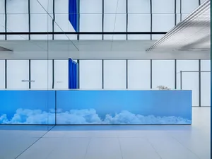 Modern office lobby with glass walls and blue digital display.
