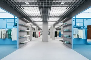 現代零售展示區，混凝土地板搭配玻璃天花板，展現服裝的當代空間氛圍。