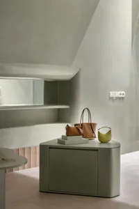 A minimalist retail shop interior displaying bags on a concrete display unit.