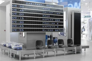 Modern airport terminal waiting area with metallic seating and digital board.