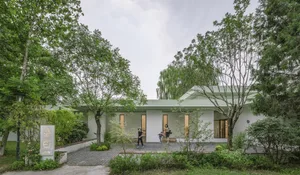 A modern house with a white brick exterior and concrete landscaping in a serene outdoor setting.