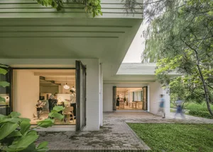 A modern living area with brick walls surrounded by greenery and open folding doors.