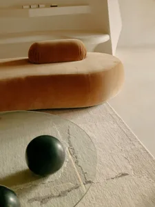 Modern round sofa upholstered in brown velvet with a minimalist living room background.