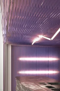 Modern interior design featuring a metallic surface with geometric patterns and industrial lighting.