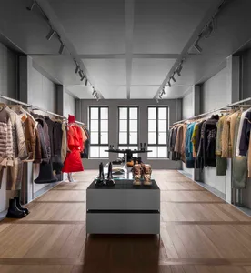 A stylish modern retail clothing store with wooden floors and clothes hanging on racks.