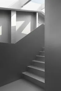 Gray concrete staircase with light shining through a skylight.
