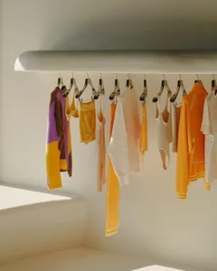 A collection of colorful clothing hangers on a white shelf.
