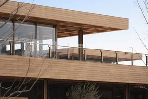 Modern exterior wooden balcony with transparent glass railings.