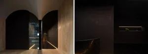 A minimalist entryway with a black marble floor and wall, featuring a subtle light strip at the base and a small green plant 