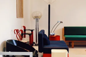 A modern living room with blue furniture, red stools, and a green couch.