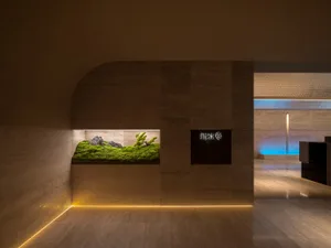 A modern lobby featuring a concrete wall with a built-in moss display and illuminated signage.