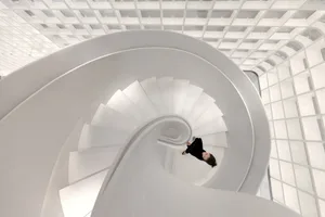 A modern, white spiral staircase with a concrete material