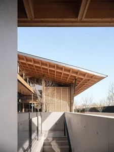 Modern wooden architectural space with a sloped roof and concrete floor.