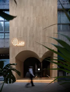 Modern minimalist spa center exterior made of concrete with illuminated signage and green foliage in the foreground.