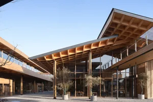 Modern minimalist building exterior featuring wooden structure, large glass windows, and concrete elements.