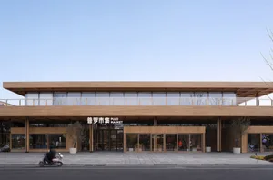 An exterior view of a modern market building with a wooden exterior and glass storefronts.