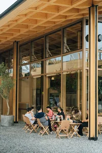 一群人坐在現代自助餐廳的桌旁，餐廳採用木框與玻璃牆設計。