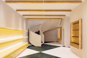 A modern commercial interior space with a unique spiral staircase featuring concrete flooring.