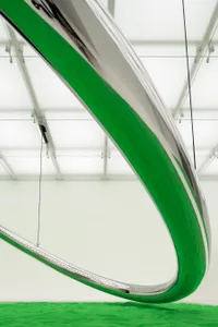 A minimalist metal installation with a green curve in a white space.