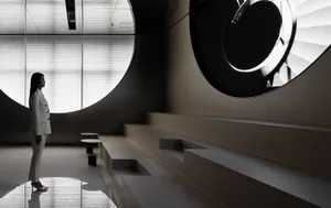 A woman standing in a modern art deco interior designed space with metal aluminum features.